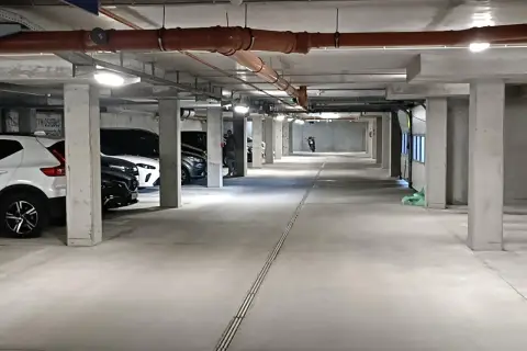 Wrocław Główny parking cennik: podziemny parking z samochodami, rurami i motocyklem w oddali.
