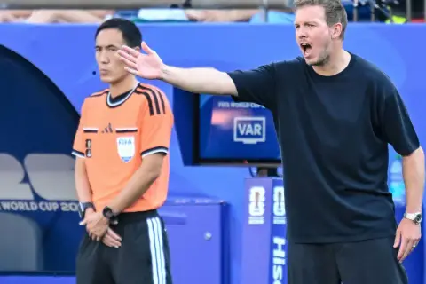 Trener Niemiec gestykuluje, dyskutując z arbitrem podczas meczu.