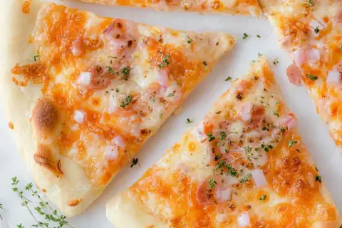 Kawałki pysznej pizzy z twarogu, posypane ziołami i kawałkami cebuli.