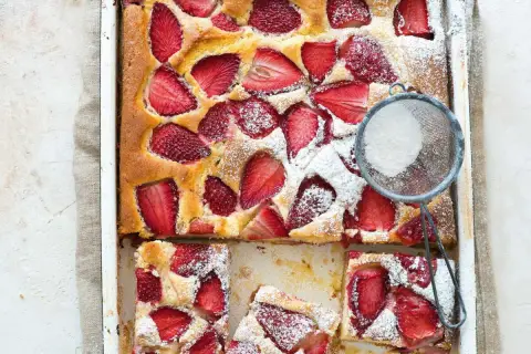 Le gâteau aux fraises de maman, doré et garni de fruits rouges, est saupoudré de sucre glace. Un délice !