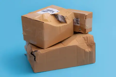 Dwie kartony, jedna na drugiej, z widocznymi uszkodzeniami i dziurami. Wygląda na to, że to uszkodzona paczka InPost.