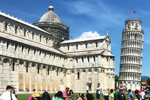 Turyści podziwiają, gdzie jest krzywa wieża w Pizie, obok katedry i baptysterium na Piazza dei Miracoli.