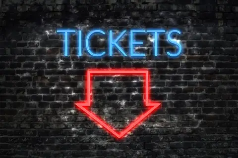 Napis "TICKETS" świeci na niebiesko nad czerwoną strzałką wskazującą w dół. To znak, jak kupić bilet online.