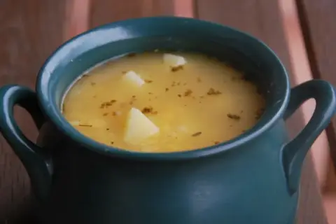 Aksamitna zupa grochowa, przepis babci, w ciemnozielonej wazie z ziemniakami i ziołami.