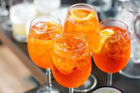 Cztery orzeźwiające drinki Aperol Spritz z lodem i plasterkami pomarańczy. Idealny aperol przepis na letnie popołudnie.