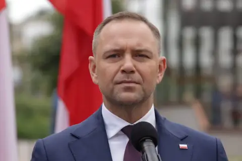 Prezydent w garniturze, obok flagi Polski, przemawia do mikrofonu. Czy prezydent może zablokować reformę renty wdowiej zaplanowaną na drugą połowę 2026 roku?