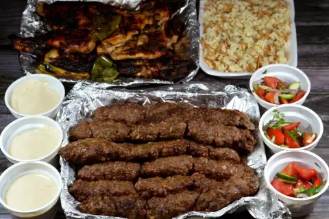 Pyszny kofta kebab z ryżem, sałatkami i sosami. Idealny posiłek dla miłośników mięsa.