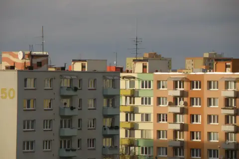 Widok na fasady bloków mieszkalnych w różnych kolorach, z balkonami i oknami.