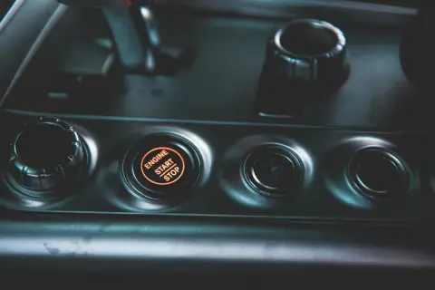 Podświetlany przycisk "ENGINE START STOP" w nowoczesnym samochodzie. Obok niego przyciski wyboru trybu jazdy.