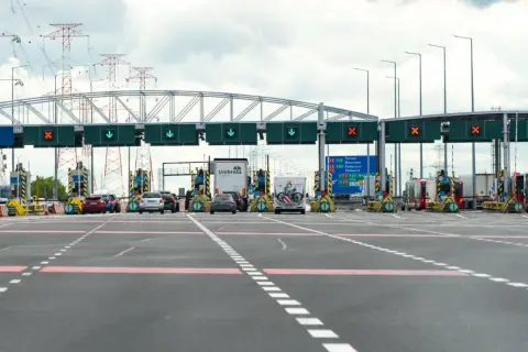 Bramki autostradowe, gdzie sprawdzisz, ile kosztuje autostrada do Zakopanego. W tle linie energetyczne.