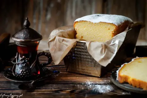 Puszysta babka włoska, oprószona cukrem pudrem, czeka na degustację obok aromatycznej herbaty w orientalnej filiżance.