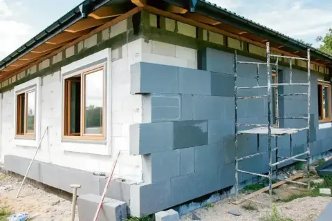 Budowa domu w toku. Szara warstwa izolacyjna na ścianie z bloczków. Sprawdzamy cenę ocieplenia za 1m2 robocizna.