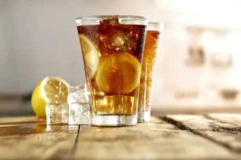 Orzeźwiający Long Island Ice Tea z cytryną i lodem na drewnianym blacie.