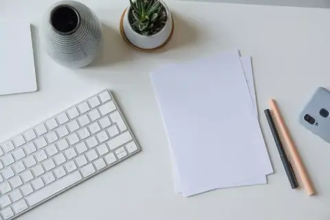 Schreibtisch mit Tastatur, Notizen, Stiften und Handy. Perfekt, um das Fernstudium zu organisieren und den Überblick zu behalten.