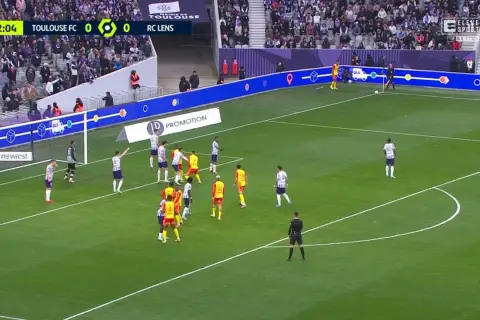 Mecz Toulouse FC - RC Lens. Piłkarze w białych i żółtych strojach szykują się do akcji pod bramką.