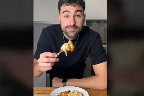Hombre sonriendo mientras prueba unos deliciosos macarrones con pollo.