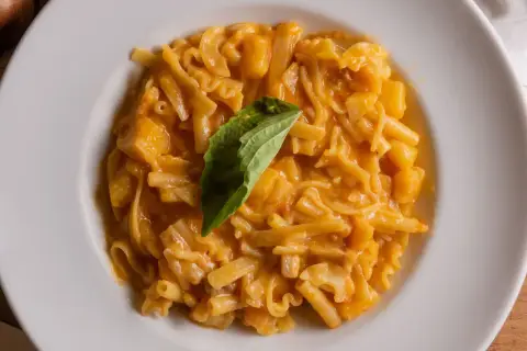 Piatto di pasta patate e provola cremoso, con un tocco di basilico fresco.