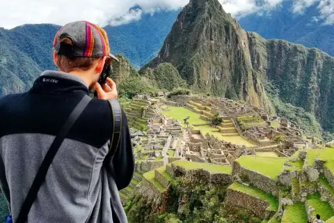 Niesamowita wycieczka do Peru! Turysta z aparatem podziwia Machu Picchu, majestatyczne ruiny Inków w otoczeniu gór.