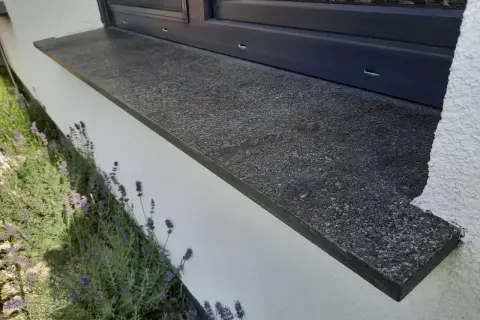Granitowy parapet zewnętrzny wystaje ok. 5 cm od ściany, chroniąc ją przed deszczem. Obok kwitnie lawenda.