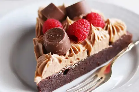 En bit kladdkaka med fluffig chokladfrosting, toppad med hallon och chokladbitar. En perfekt kombination för alla chokladälskare.