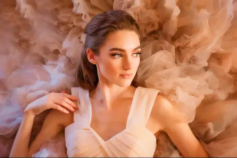 A beautiful woman in a flowing gown, captured in a dreamy fine art portrait photography style, surrounded by soft, ethereal fabric.