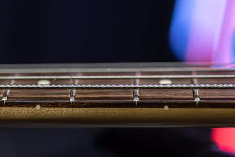 Gros plan sur les cordes et les frettes d'une guitare, révélant le radius subtil du manche.