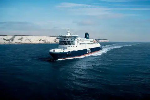 Duży prom DFDS płynie po wzburzonym morzu w kierunku białych klifów. To widok na trasie do Dunkierki.
