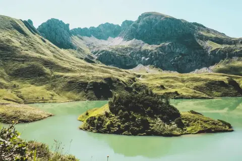A serene lake reflects the rugged peaks of the Bavarian Forest. Perfect for **wandern im Bayerischen Wald**, this landscape offers a peaceful escape.