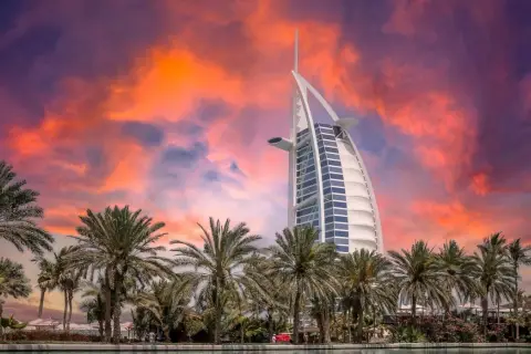 Zachód słońca nad Dubajem, palmy i hotel Burdż al-Arab. Zastanawiasz się, ile kosztuje wycieczka do Dubaju?