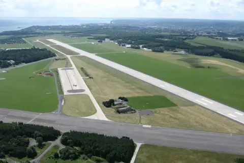 Lotnisko w Gdyni z lotu ptaka. Widać pasy startowe, trawiaste tereny i budynki.