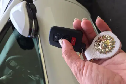 Uszkodzony transponder w kluczyku objawy: auto nie odpala, miga kontrolka. Dłoń trzyma kluczyk z breloczkiem w kształcie słońca.