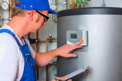 Instalacja ogrzewania gazowego: monter sprawdza panel sterowania bojlerem, notując dane na kartce.