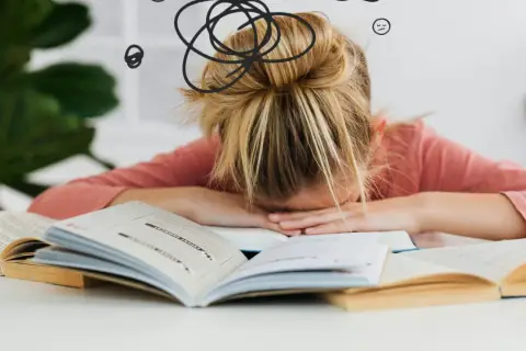 Dziewczynka z blond włosami w koku, zmęczona nauką, opiera głowę na otwartych książkach. Wokół jej głowy rysunki symbolizujące chaos i zmęczenie.