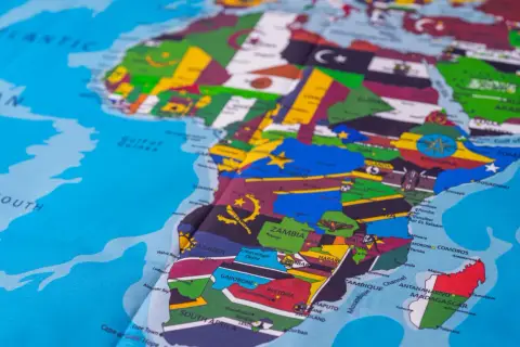 Mapa świata z zaznaczoną Afryką, która jest kontynentem. Widoczne flagi państw i nazwy miast.