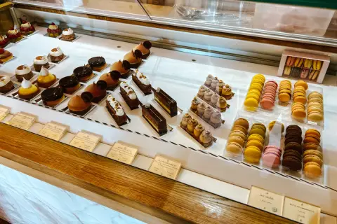 Witryna cukierni z wykwintnymi deserami, w tym makaronikami i ciastkami, idealna dla szukających najlepszych francuskich restauracji.