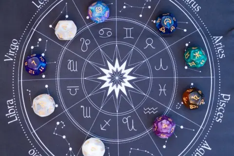 Kości do gry z symbolami zodiaku i cyframi, w tym kostka z numerologiczną 10, leżą na tle wykresu astrologicznego.