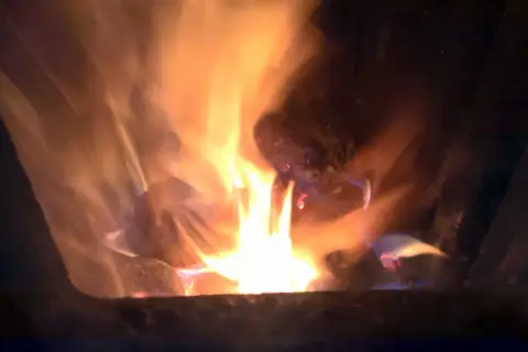 Jasne płomienie tańczą wokół żarzących się brykietów ze słomy, tworząc ciepłą, przytulną atmosferę.