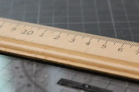 Une règle en bois sur un tapis de découpe, ses graduations formant une signature rythmique parfaite pour mesurer.