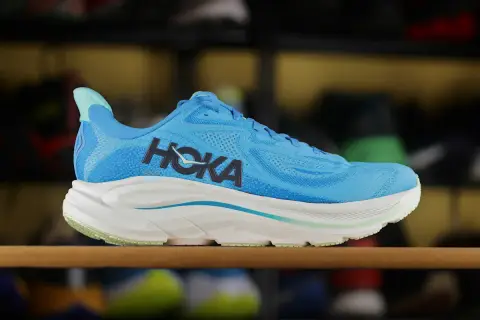 Niebieskie buty sportowe Hoka z charakterystycznym logo. To firma znana z innowacyjnych rozwiązań w obuwiu biegowym.