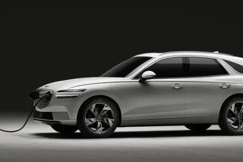 Biały Genesis GV70 na ładowarce. Elegancki SUV z charakterystycznym grillem i światłami LED.