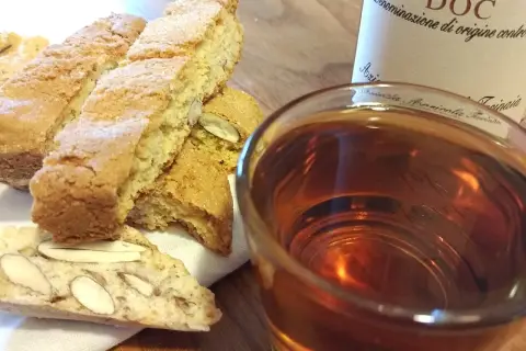 Cantuccini mit Mandeln und ein Glas süßer Dessertwein aus der Toskana, perfekt für einen Genussmoment.