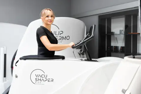 Kobieta ćwiczy na rowerze Vacu Shaper, by osiągnąć wymarzone efekty.