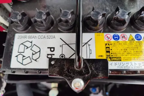Mitsubishi Space Star Batterie wechseln: Das Bild zeigt eine Autobatterie mit Warnhinweisen und Spezifikationen wie 20HR 66Ah CCA 520A.