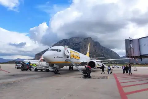 Samolot Buzz by Ryanair na lotnisku na Sycylii, z górami w tle.