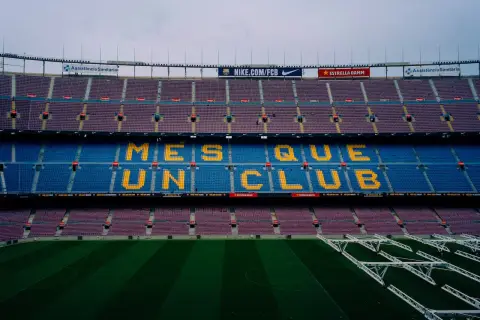 Trybuny Camp Nou z napisem "Més que un club" w żółtych literach, symbolizującym hymn Barcelony.