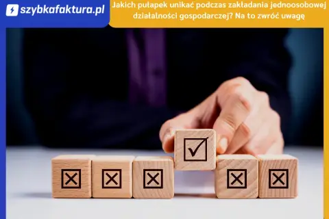 Dłoń układa kostki z symbolami. Jedna z nich, z zaznaczonym ptaszkiem, symbolizuje sukces w jdg.