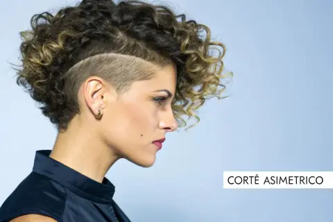 Mujer con pelo corto rizado y rapado asimétrico. Un estilo audaz que resalta su personalidad.