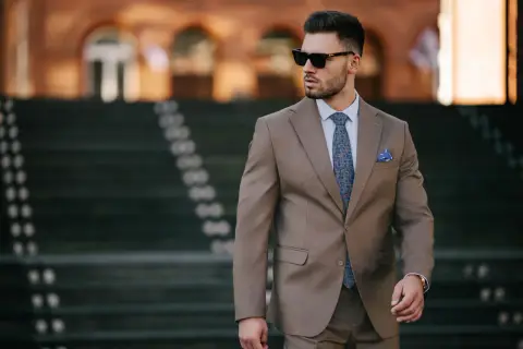 Elegancki mężczyzna w garniturze, z wzorzystym krawatem i poszetką. Czy to butonierka co to?
