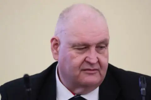 Jan Kowalski, syn Wacława Kowalskiego, w garniturze, z mikrofonem przed sobą.