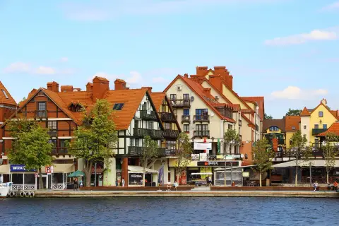 Urokliwa nadmorska promenada z kolorowymi kamieniczkami, jak z bajki o Mikołajkach w Warszawie.
